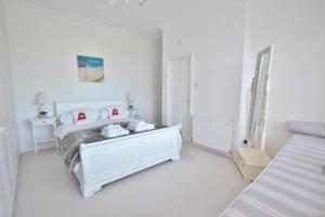 a white bedroom with a bed and a mirror at Springhill House in Swanage