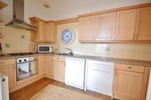 una cocina con armarios de madera y un reloj en la pared en Springhill House, en Swanage