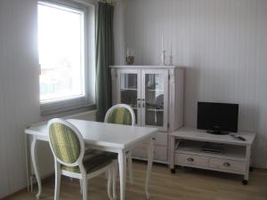 a living room with a white table and chairs and a tv at Ferienwohnung Meeresblick in Zierow