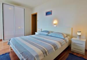 a bedroom with a large bed with blue and white sheets at Apartments Eufemija in Rab