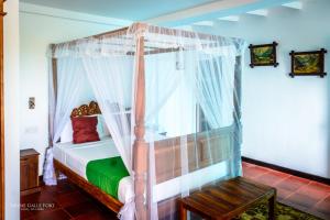 a bedroom with a canopy bed and a bench at Sirène Galle Fort in Galle