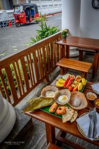 einen Tisch mit Frühstückszutaten auf einer Holzbank in der Unterkunft Sirène Galle Fort in Galle