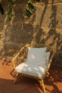 een rieten stoel met een wit kussen voor een muur bij Refúgio de Calheiros in Covilhã