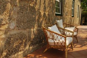 dwa krzesła siedzące obok kamiennej ściany w obiekcie Refúgio de Calheiros w mieście Covilhã