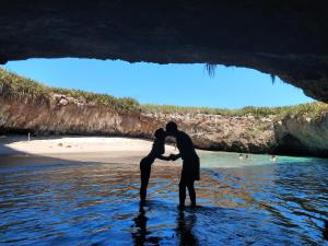 a couple kissing in the water in front of a cave at Apartamento Pelicanos, Nuevo Vallarta in Nuevo Vallarta