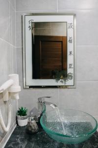 uma casa de banho com um lavatório de vidro e um espelho. em OASIS Teplice em Teplice