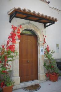 a wooden door in a building with red flowers at Medieval Village of Pacentro in Pacentro