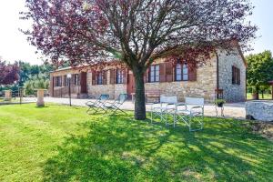 um grupo de cadeiras sentadas sob uma árvore em um quintal em Agriturismo Il Falco em Todi