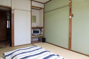 een lege kamer met een bed en een televisie bij TSUKASA HOUSE English OK Kumano Kodo experience Lodge Close to station 無料駐車場あり in Tanabe