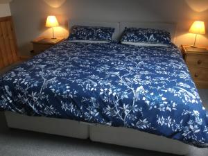 a bed with a blue comforter and two lamps at Tyddyn Perthi Farm in Llanberis