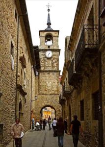 people walking down a street with a clock tower at La Encina Azul Rooms in Ponferrada