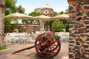 a woodenokedoked wheel with umbrellas on a patio with tables at Hotel Ex Hacienda La Pitaya Querétaro in Villa del Pueblito