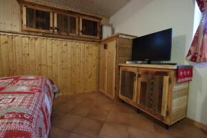 1 dormitorio con TV de pantalla plana en un armario de madera en La Belette, en La Thuile