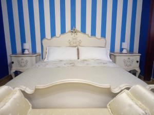a bedroom with a white bed with blue and white stripes at Villa sullo stretto in SantʼAgata
