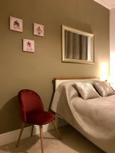 a bedroom with a bed and a red chair at Velvet Nest 5 min walk from train station in Leamington Spa