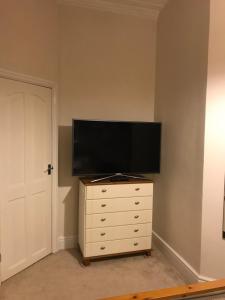 a flat screen tv on top of a dresser at Velvet Nest 5 min walk from train station in Leamington Spa