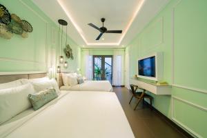 um quarto com uma grande cama branca e uma televisão em Lavini Hoian Boutique Villa em Hoi An