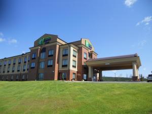 a building with a grass field in front of it at Holiday Inn Express Greensburg, an IHG Hotel in Greensburg