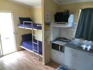 a kitchen with a sink, microwave, and refrigerator at Karumba Point Sunset Caravan Park in Karumba