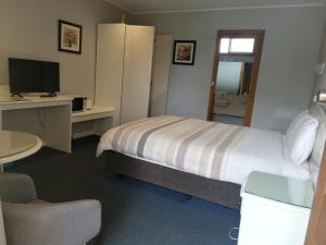 a hotel room with a bed, desk, and mirror at Casey on Princes Motel in Hallam