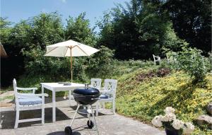 a grill and a table with chairs and an umbrella at One-Bedroom Holiday Home In Christiansfeld in Christiansfeld
