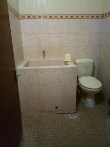 a bathroom with a toilet and a bath tub at Prayogo Lama Family GH Prawirotaman in Yogyakarta +30 photos