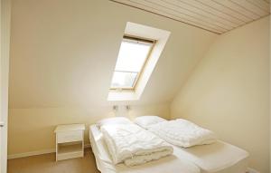 Un dormitorio con una cama con sábanas blancas y una ventana. en Two-Bedroom Apartment In Gudhjem, en Gudhjem