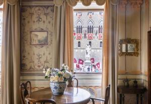 un vaso di fiori su un tavolo di fronte a una finestra di Domus Nannini SPA - Palazzo Nannini a Siena