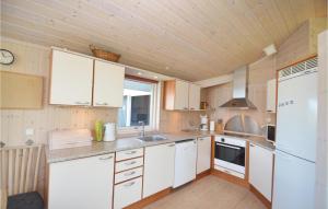 a kitchen with white cabinets and a wooden ceiling at Holiday Home Elsdyrstien Væggerløse Vi in Marielyst +11 photos