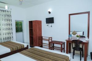 1 Schlafzimmer mit 2 Betten, einem Schreibtisch und einem Tisch in der Unterkunft Bon Voyaage Tourist Inn in Trincomalee