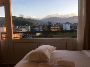 a bedroom with a window with a view of mountains at Hotel Lilyland Pvt Ltd in Pokhara +18 photos