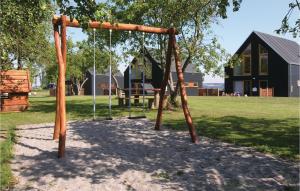 a swing set in a park with a house at Holiday Home Kongsnæsparken Iv in Stubbekøbing