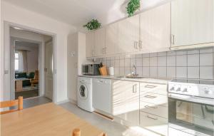 アリンエにある1 Bedroom Amazing Apartment In Allingeの白いキャビネットとテーブル付きのキッチンが備わります。