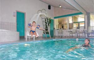a young boy sitting on a water slide in a swimming pool at Awesome Home In Lkken With Indoor Swimming Pool in Lønstrup