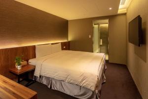 Habitación de hotel con cama y TV en Goodmore Hotel, en Taipéi