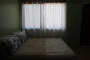 1 cama en un dormitorio con ventana en Yoo C Apartment, en Dumaguete