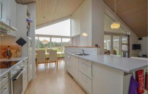 uma cozinha com armários brancos e uma grande janela em Sanglrken em Øksenmølle
