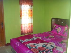 1 dormitorio con cama con sábanas rosas y ventana en Cahyo Homestay Bromo, en Bromo