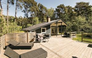 a house with a deck with a table and chairs at Holiday Home Munkegårdsskoven Nexø Ix in Spidsegård