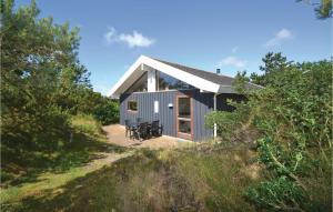a gray house on top of a hill with trees at Amazing Home In Fan With Kitchen in Fanø