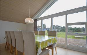 ein Esszimmer mit Tisch und Stühlen und Fenstern in der Unterkunft Sanglærken in Øksenmølle