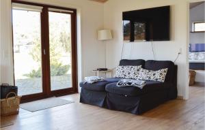 3 Bedroom Awesome Home In Jgerspris في Hornsved: غرفة معيشة مع أريكة زرقاء وباب زجاجي منزلق