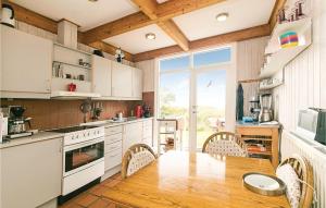 グドイェムにあるAmazing Home In Gudhjem With 3 Bedrooms And Wifiのキッチン(テーブル、椅子付)、大きな窓が備わります。