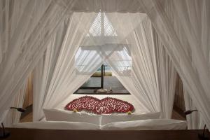 a white bed with a canopy and a window at Jeeva Beloam Beach Camp in Tanjung Ringgit