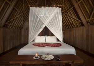 a bedroom with a bed with a candle and a table at Jeeva Beloam Beach Camp in Tanjung Ringgit