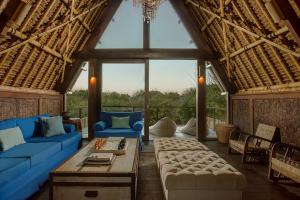 a living room with blue couches and a large window at Jeeva Beloam Beach Camp in Tanjung Ringgit