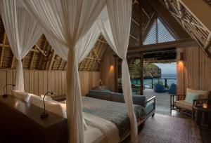 a bedroom with a canopy bed with a view of the ocean at Jeeva Beloam Beach Camp in Tanjung Ringgit