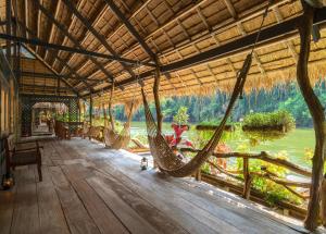 a room with hammocks and a view of a river at River Kwai Jungle Rafts - SHA Extra Plus in Sai Yok
