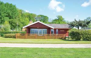 czerwony dom z drewnianym płotem w trawie w obiekcie Stunning Home In Egernsund With Kitchen w mieście Egernsund