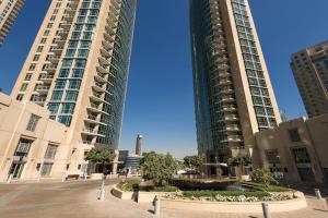 Burj Residences T3 Premium Apartment في دبي: مبنيان طويلان في مدينة بها نافورة بينهما